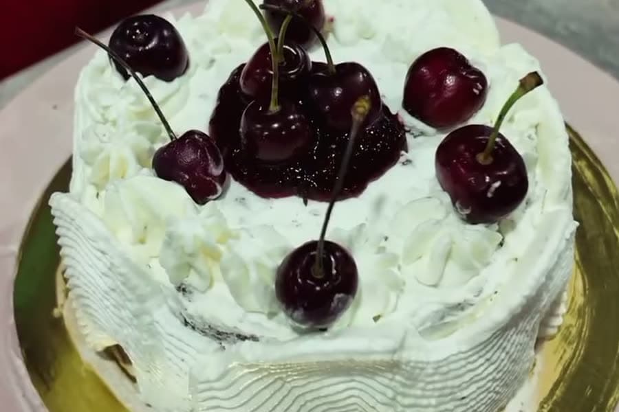 Gâteau bento à la crème et aux cerises fraîches sur un plateau doré