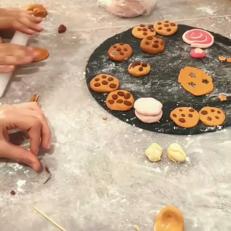 Des mains d'enfants décorent des biscuits sur une ardoise