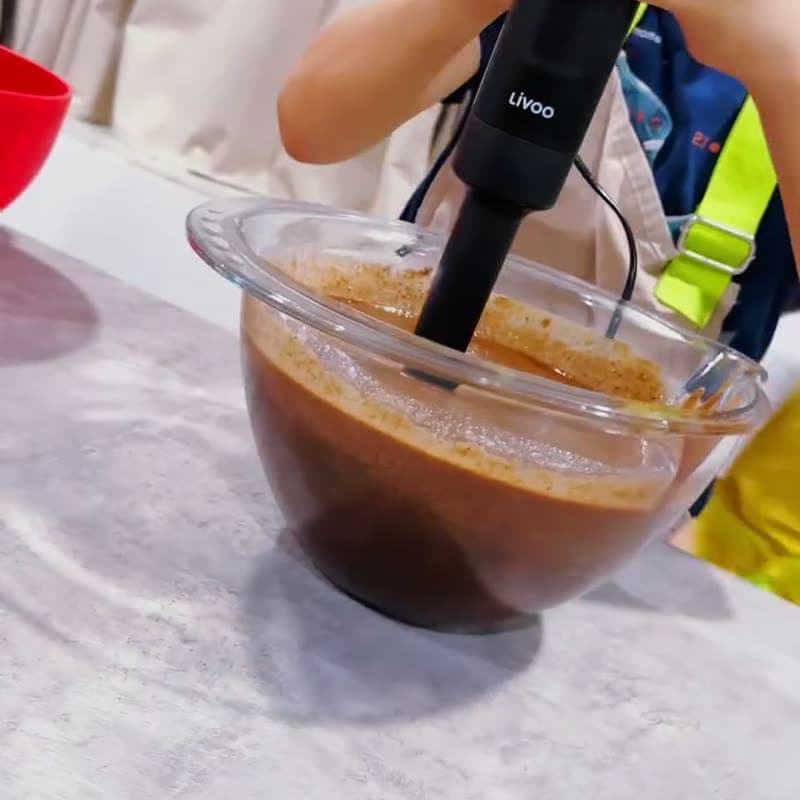 Un enfant mixe une préparation au chocolat au mixeur plongeant